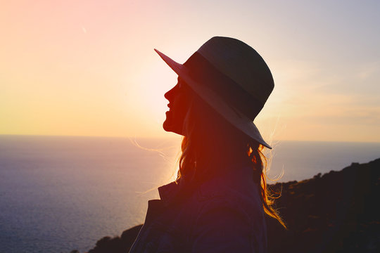 Young emotional woman enjoying sunset on cliff silhouette
