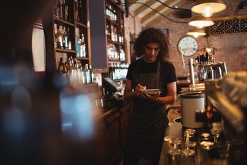 Young waiter writing on diary