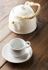 From above white ceramic mug and pot placed on the wooden background.