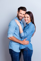 Vertical photo of two young cheerful people hugging each other against gray backdrop