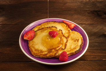 Honey poured over homemade pancakes with fresh fruit