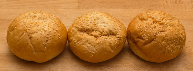 Three hamburger rolls on the wood