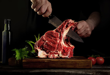 Man cutting raw beef meat. - obrazy, fototapety, plakaty
