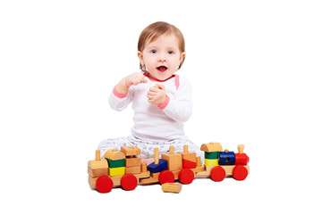 Beautiful baby girl playing a wooden train, isolated on a white background