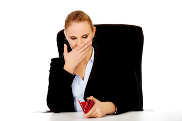 Worried business woman sitting behind the desk with empty wallet