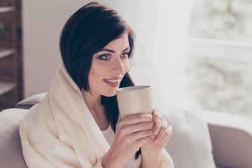 Weekends! Cute girl is drinking her coffee at home, covered by blanket. She feels so good and cozy