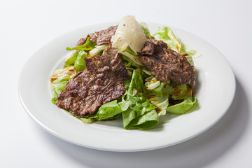 Beef salad with lettuce and cheese on a white plate