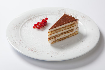 tiramisu on a white plate decorated with red currants
