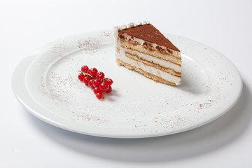 tiramisu on a white plate decorated with red currants