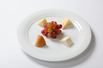 Assorted cheeses and grape on a white plate