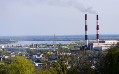 Fototapeta na wymiar Industrial landscape. The view on a factory pipes polluting the atmosphere.