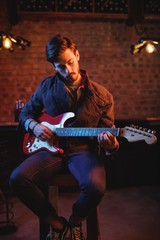 Obraz premium Concentrate male playing guitar in pub