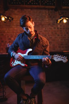 Concentrate male playing guitar in pub