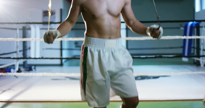 A professional boxer in the gym, jumping rope, improving endurance, speed and sharpness, excellent body and training, in white sportswear. Concept: love of sport, young boxers, love to win