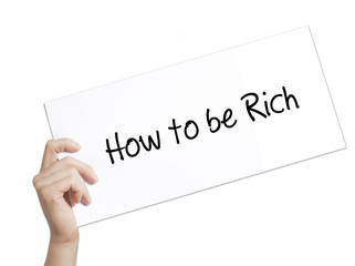 How to be Rich  Sign on white paper. Man Hand Holding Paper with text. Isolated on white background