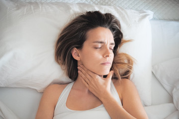 Donna a letto con mal di gola e dolori