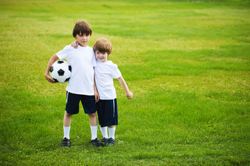 Two boys with a soccer ball on a football field.