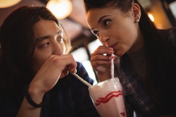 Close-up of couple having milkshake