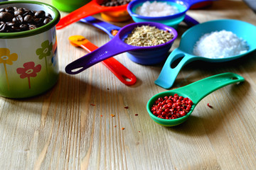 Spices, herbs, salt, sugar, coffee beans in multicolored measuring spoons and cups