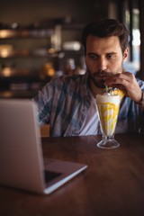 Man using laptop while having milkshake
