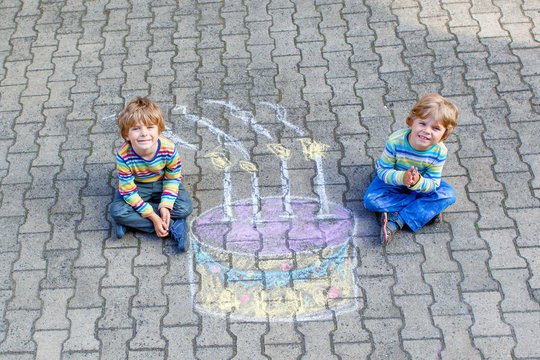 Two kid boys having fun with colorful birthday cake drawing with