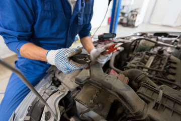 auto mechanic man with cleats charging battery