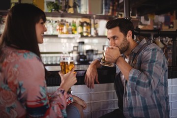 Couple interacting while having beer at counter