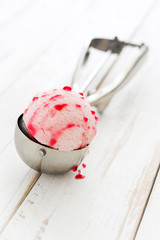 Strawberry ice cream scoop on white wooden table


