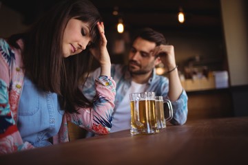 Sad couple having beer at counter