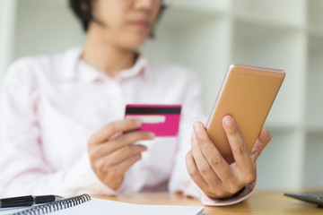 Woman's hands holding a credit card for payment and using smart phone for online shopping