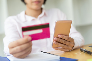 Woman's hands holding a credit card for payment and using smart phone for online shopping