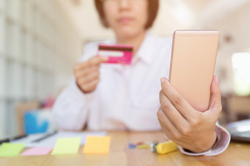 Woman's hands holding a credit card for payment and using smart phone for online shopping