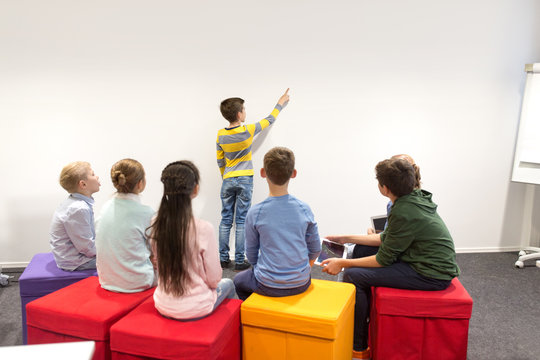 student boy with friends showing to white wall