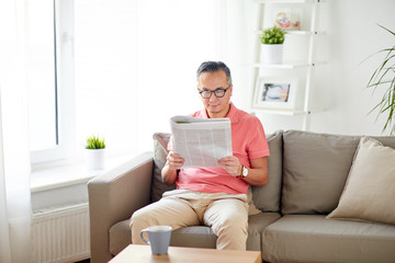 happy man in glasses reading newspaper at home