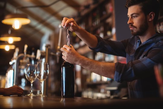 Male Bar Tender Opening A Bottle Of Wine