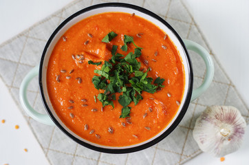 Lentil  tomato cream soup in a rustic bowl with garlic.