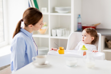 Obraz na płótnie Canvas happy mother and baby having breakfast at home