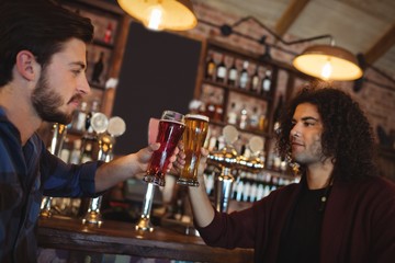 Friends toasting glasses of beer at bar counter