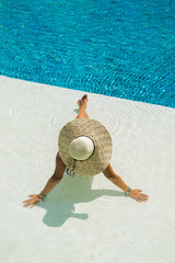 Fototapeta na wymiar beautiful woman in a hat sitting on the edge of the pool