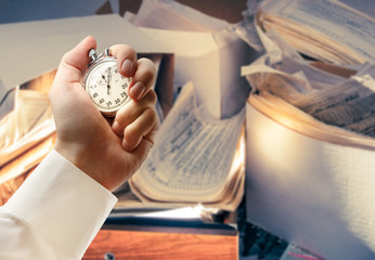 Messy workplace and stopwatch in hand