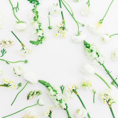Round frame made of white ranunculus, snapdragon and tulip on white background. Flat lay, top view. Background of spring flowers