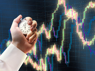 Candlestick chart and stopwatch in male hand