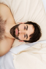 Obraz na płótnie Canvas Young muscular man lying in bed.
