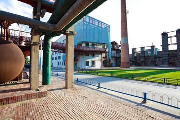 Empty red brick road surface floor with old steel steelworks of pipelines