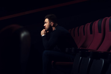 Fototapeta premium Handsome young man watching movie in theater