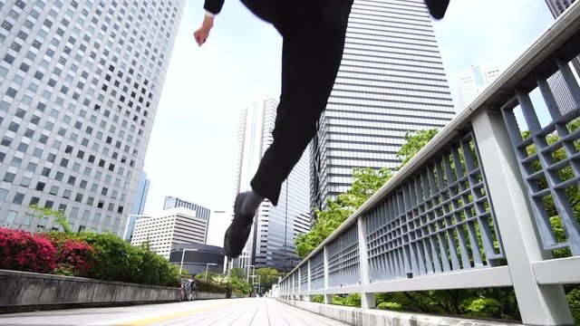 スーローモーション　ジャンプして走る　ビジネスマン　新宿ビジネス街　正面