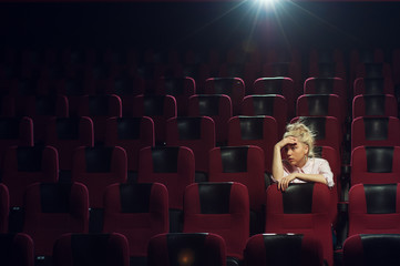 Young caucasian woman sitting in cinema theater