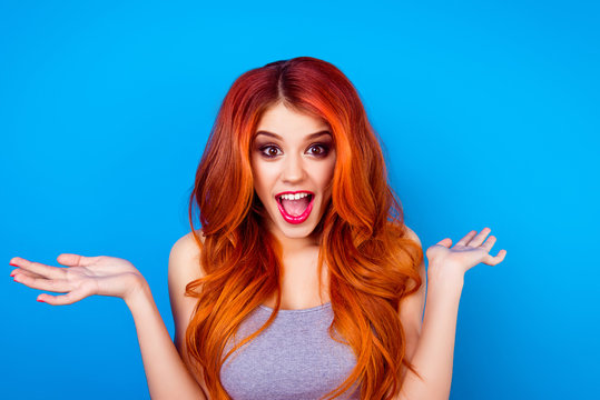 Close-up portrait of attractive cute girl with long ginger with dye ombre fair hair and surprised face holding hands and open mouth while standing on blue background