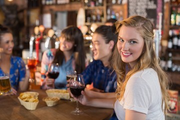 Portrait of smiling woman holding drink with friends