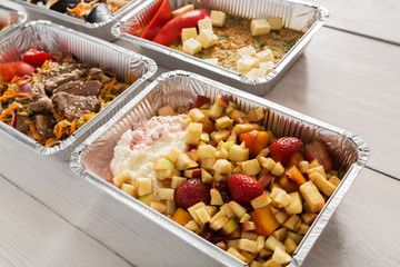 Healthy food take away in foil boxes on wood background